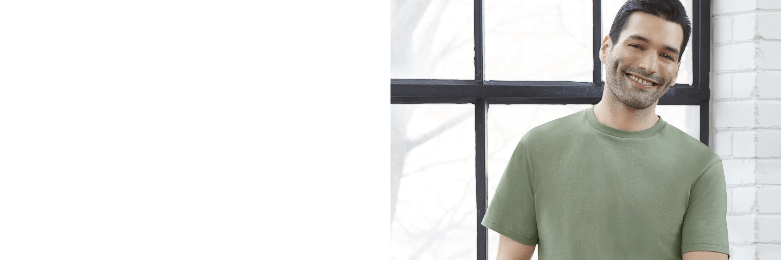 Man wearing a green t-shirt standing in front of a window with white brick wall background